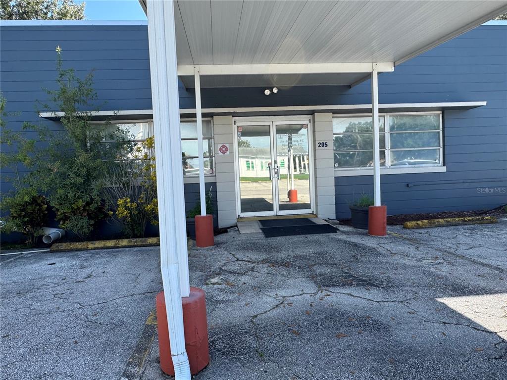 The exterior of a blue building features a covered entrance and glass double doors — 205 N SCENIC HIGHWAY, FROSTPROOF, FL