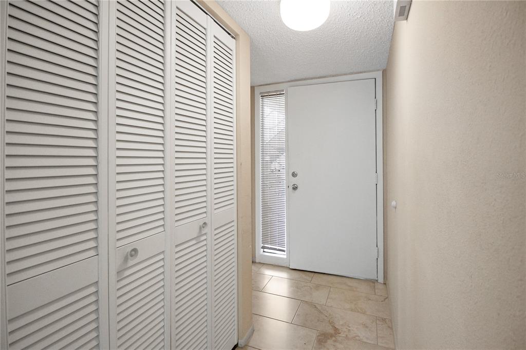 An entryway features white louvered closet doors, tile flooring, and a white front door — 135 WOODLAKE WYNDE UNIT 135, OLDSMAR, FL