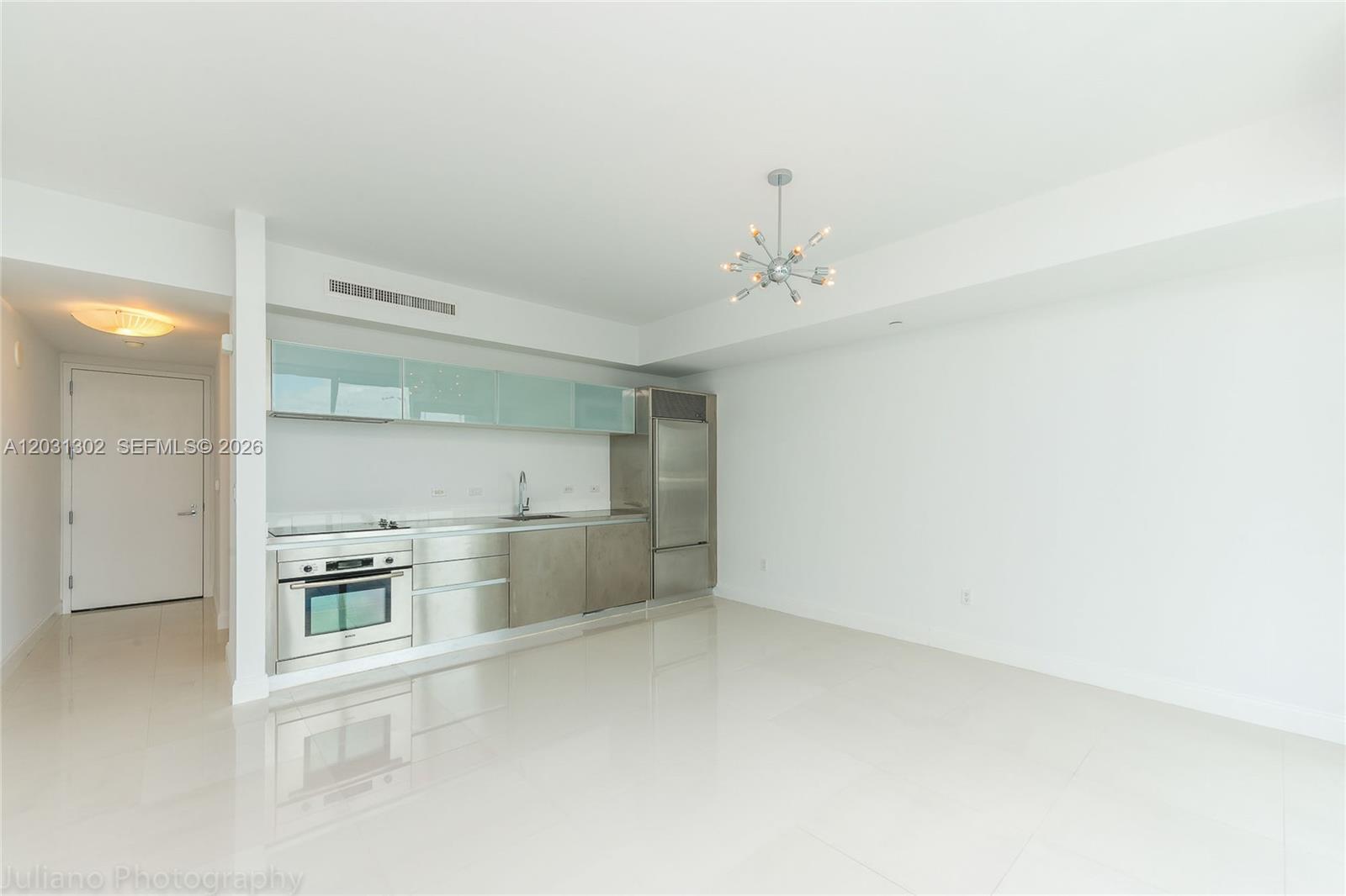 A modern kitchen features stainless steel appliances, light blue upper cabinets, and white tile flooring — 1040 Biscayne Blvd # 1205, Miami FL 33132, MIAMI, FL