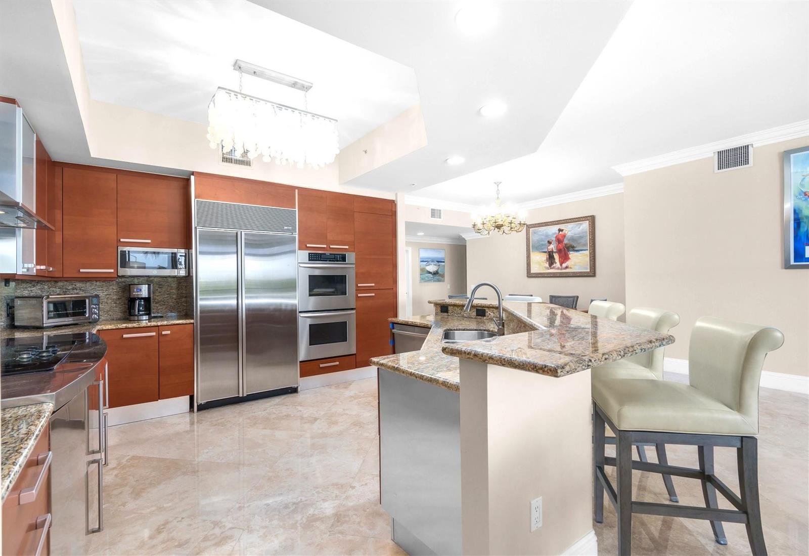A kitchen features wood cabinets, stainless steel appliances, granite countertops, and a breakfast bar — 701 SE 21st Avenue # 304, Deerfield Beach FL 33441, DEERFIELD BEACH, FL