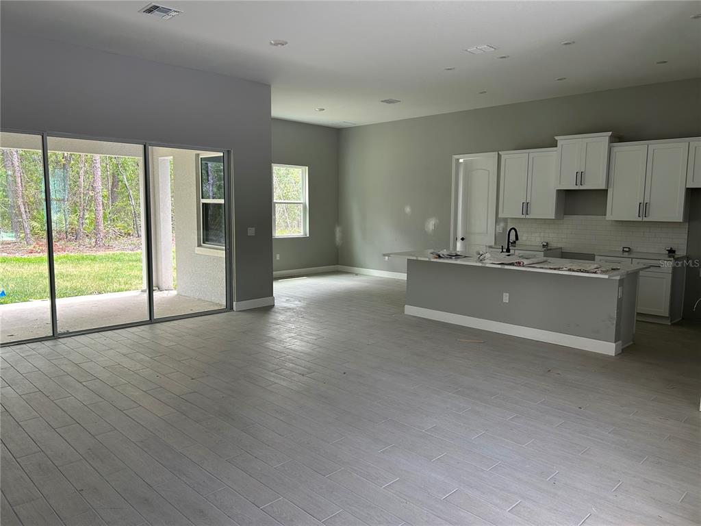 An open-concept kitchen and living area features light gray tile flooring and white cabinetry — 42 VILLAGE CENTER DRIVE, HOMOSASSA, FL
