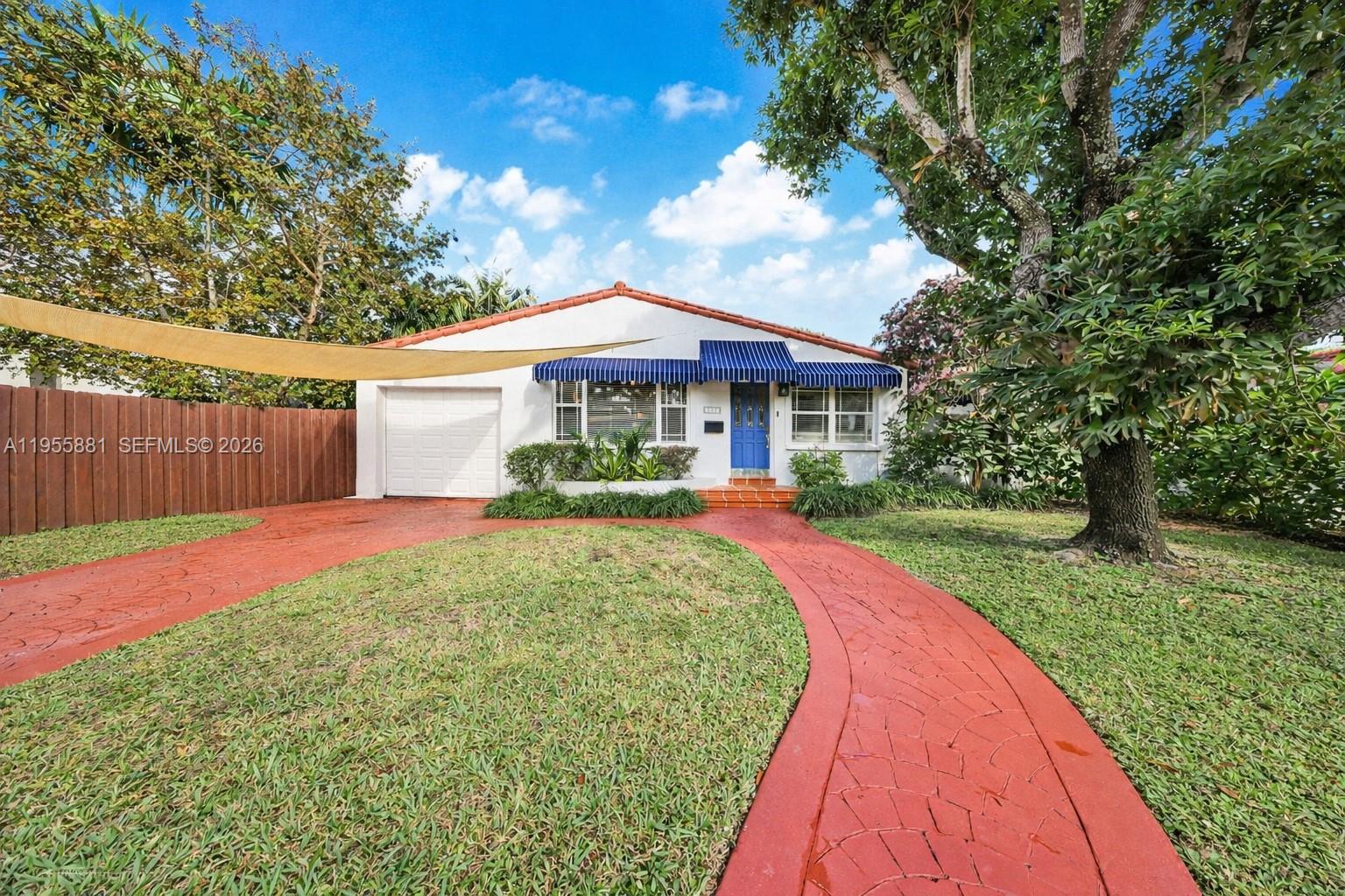 A single-story house features a red stamped concrete driveway, blue awnings, and a blue door — 717 NE 73rd St, Miami FL 33138, MIAMI, FL