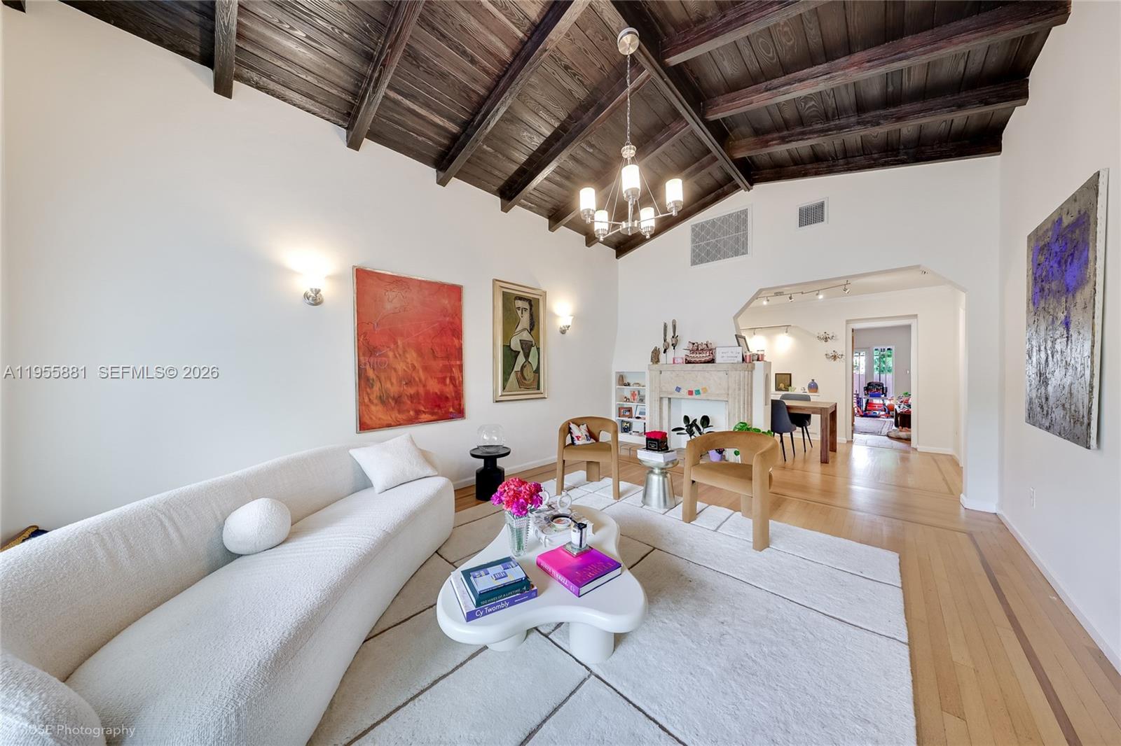 A living room features a vaulted wood-beamed ceiling, white walls, and a modern white sofa — 717 NE 73rd St, Miami FL 33138, MIAMI, FL