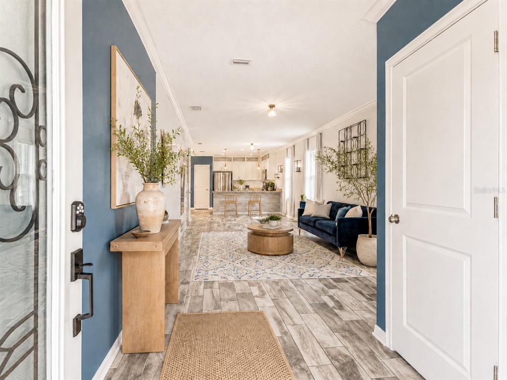 A view from an entryway into a living room and kitchen with wood-look tile flooring — 2601 E LAKE AVENUE UNIT A, TAMPA, FL