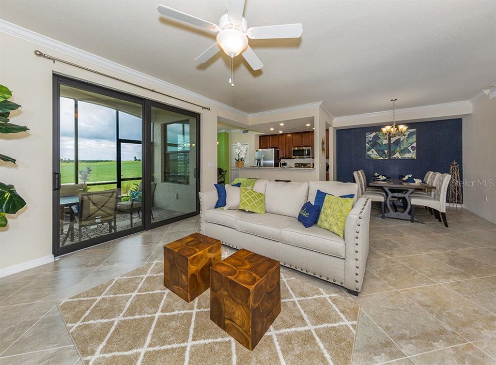 A living room with a beige sofa, two wooden cube tables, and a sliding glass door — 5548 PALMER CIRCLE UNIT 103, BRADENTON, FL