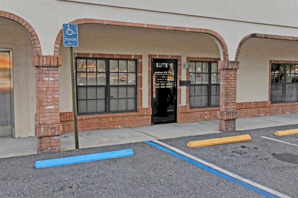The exterior of a commercial building features a brick-trimmed storefront with a glass door — 5330 SPRING HILL DRIVE UNIT A, SPRING HILL, FL