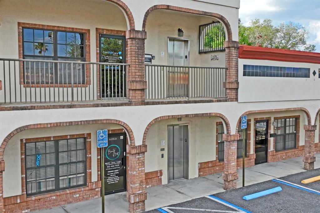 An exterior view of a two-story commercial building with brick columns and metal railings — 5330 SPRING HILL DRIVE UNIT A, SPRING HILL, FL