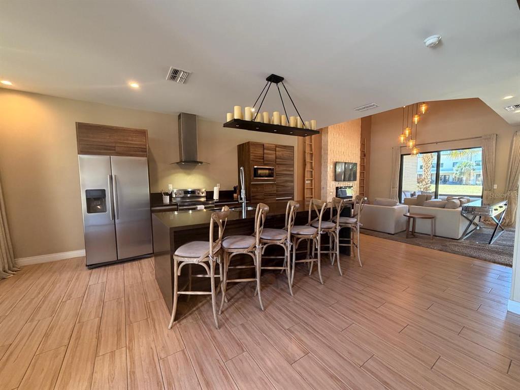 A kitchen with a dark wood island and bar stools opens into a living area — 7464 BROOKLYN DRIVE, KISSIMMEE, FL
