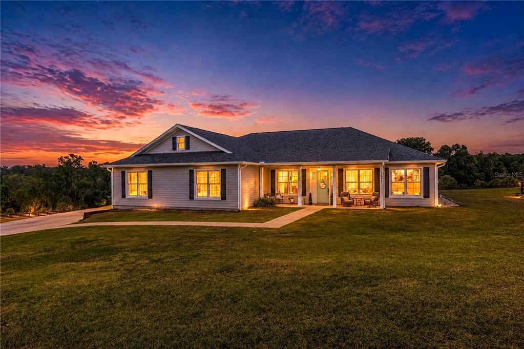 A single-story house with light siding and a covered porch stands at sunset — 5021 NW 101ST STREET ROAD, OCALA, FL