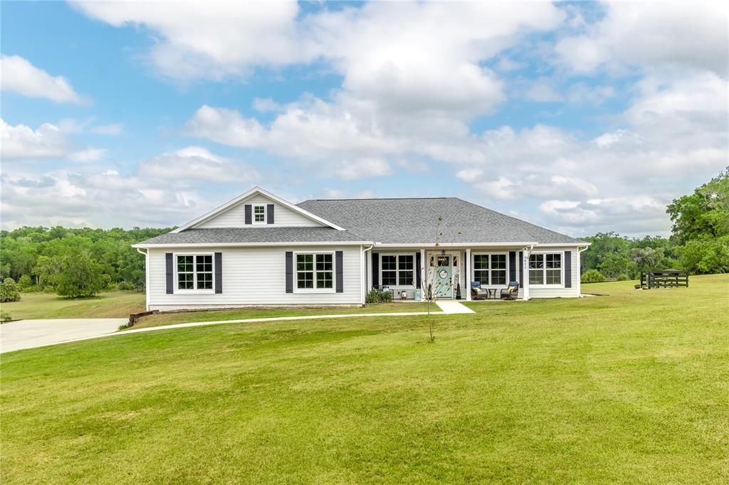 A white single-story house with dark shutters sits on a large, grassy rural lot — 5021 NW 101ST STREET ROAD, OCALA, FL