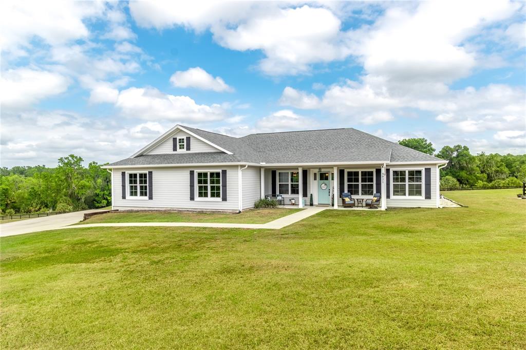 A single-story house with light gray siding, a gray shingled roof, and a front porch — 5021 NW 101ST STREET ROAD, OCALA, FL