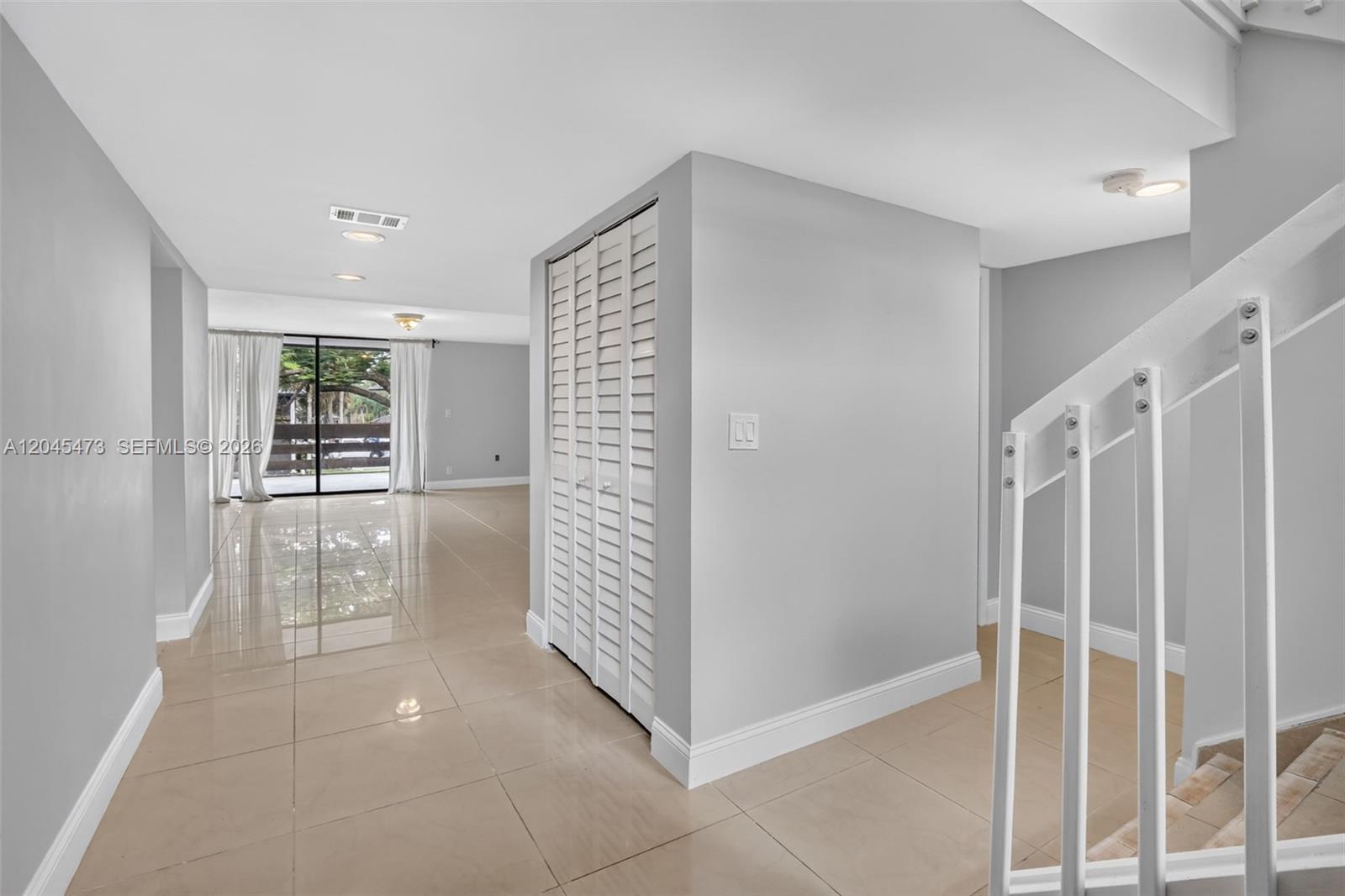 A bright room features light-colored tile flooring, a central closet with louvered doors, and stairs — 120 SW 96th Ter # 204, Plantation FL 33324, PLANTATION, FL