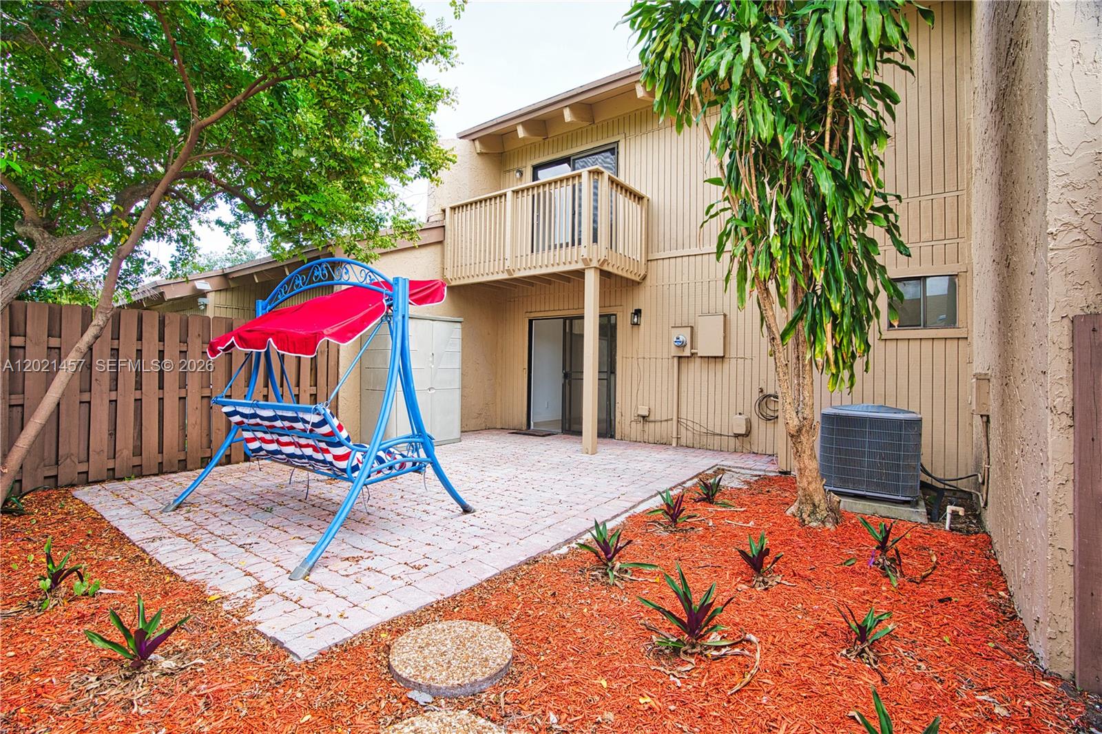 A backyard patio features a red-and-blue swing, a wooden fence, and a two-story building — 8015 SW 21st Ct, Davie FL 33324, DAVIE, FL