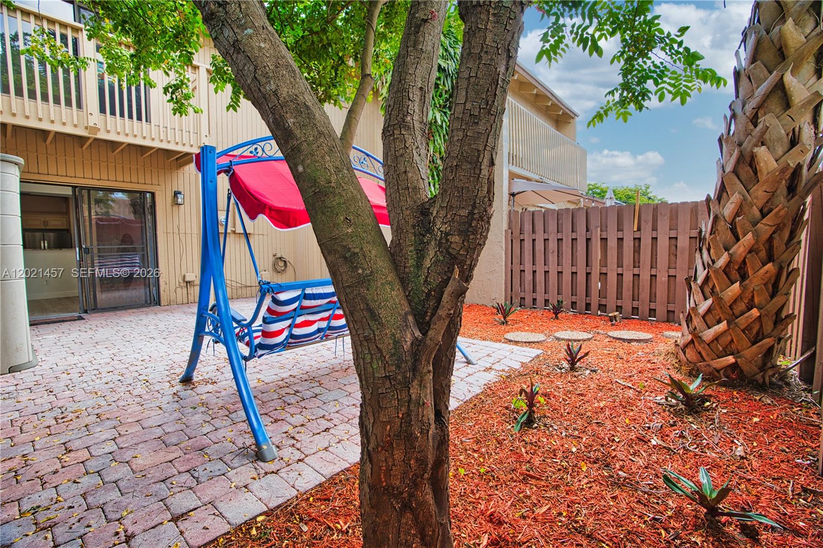 A patio features a blue porch swing, brick pavers, and a small garden area — 8015 SW 21st Ct, Davie FL 33324, DAVIE, FL