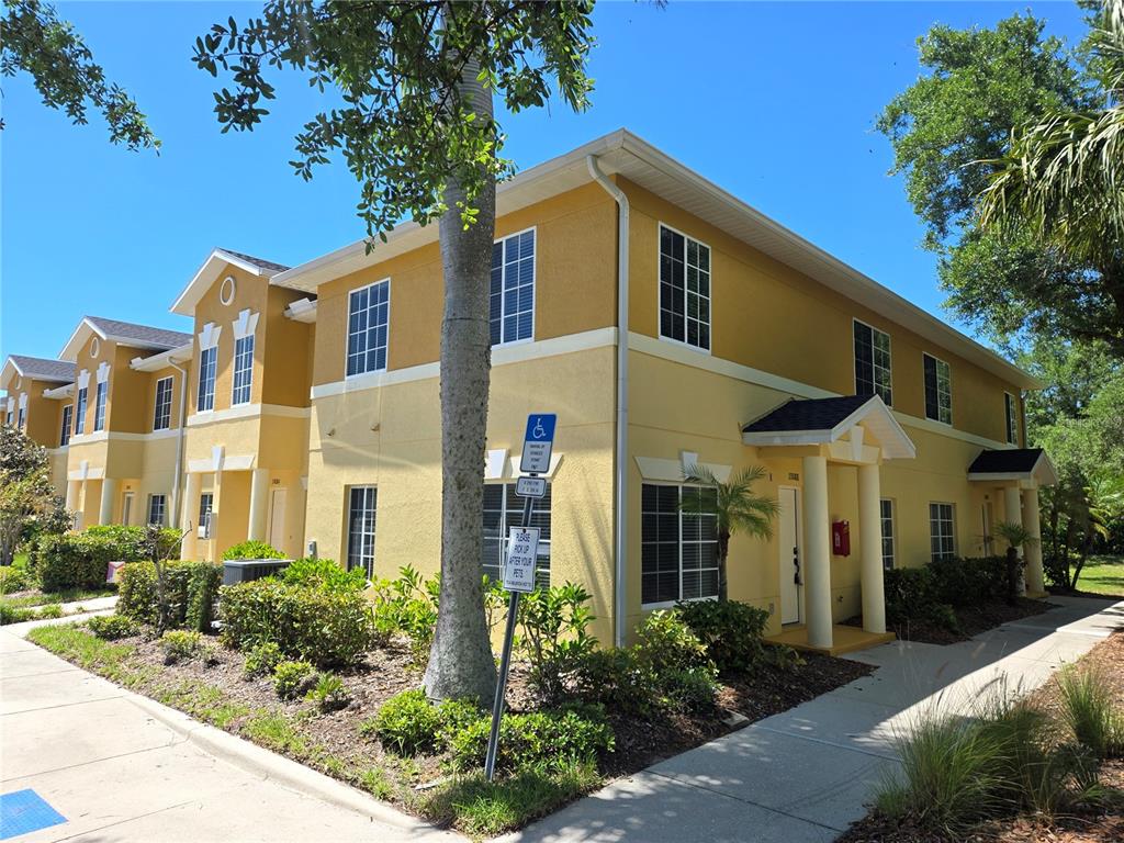 A two-story yellow apartment building with a sidewalk and landscaping in front — 13088 TIGERS EYE DRIVE, VENICE, FL