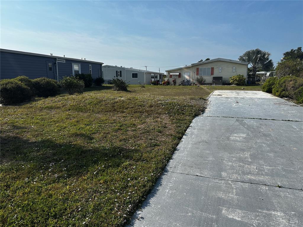 A vacant lot with a concrete driveway sits between two manufactured homes under a clear sky — 206 SCHOONER STREET, NORTH PORT, FL