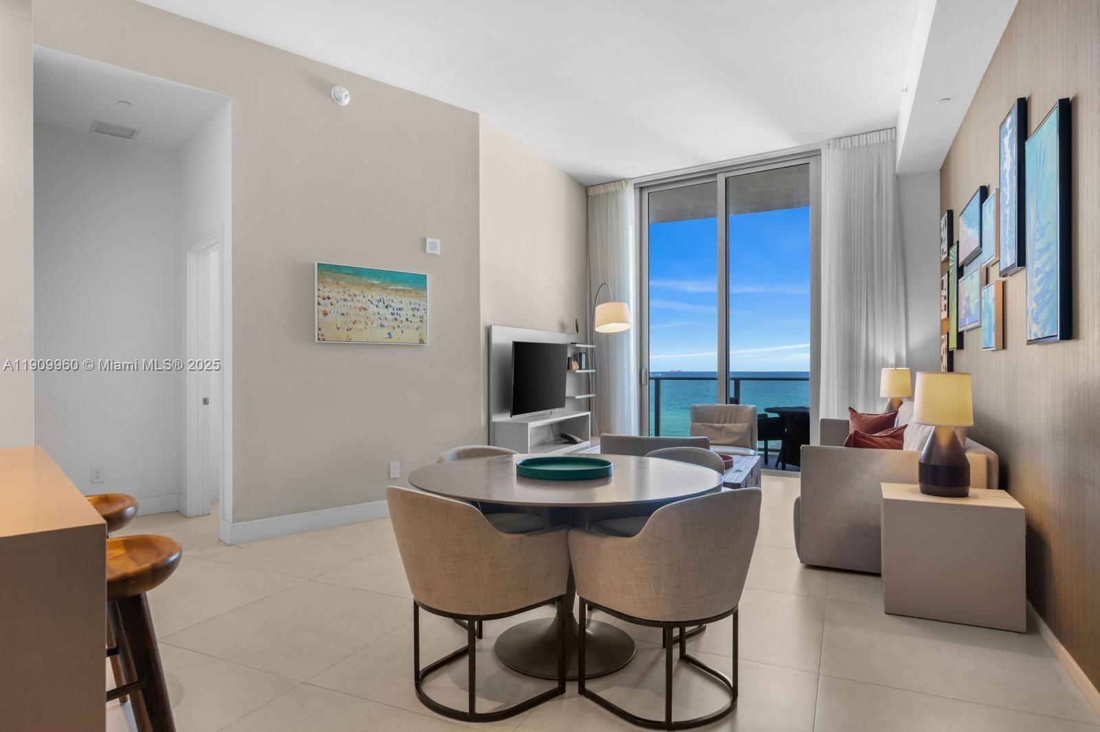 A modern living and dining area features a round table, sofa, and ocean view balcony — 4111 S Ocean Dr # 502, Hollywood FL 33019, HOLLYWOOD, FL