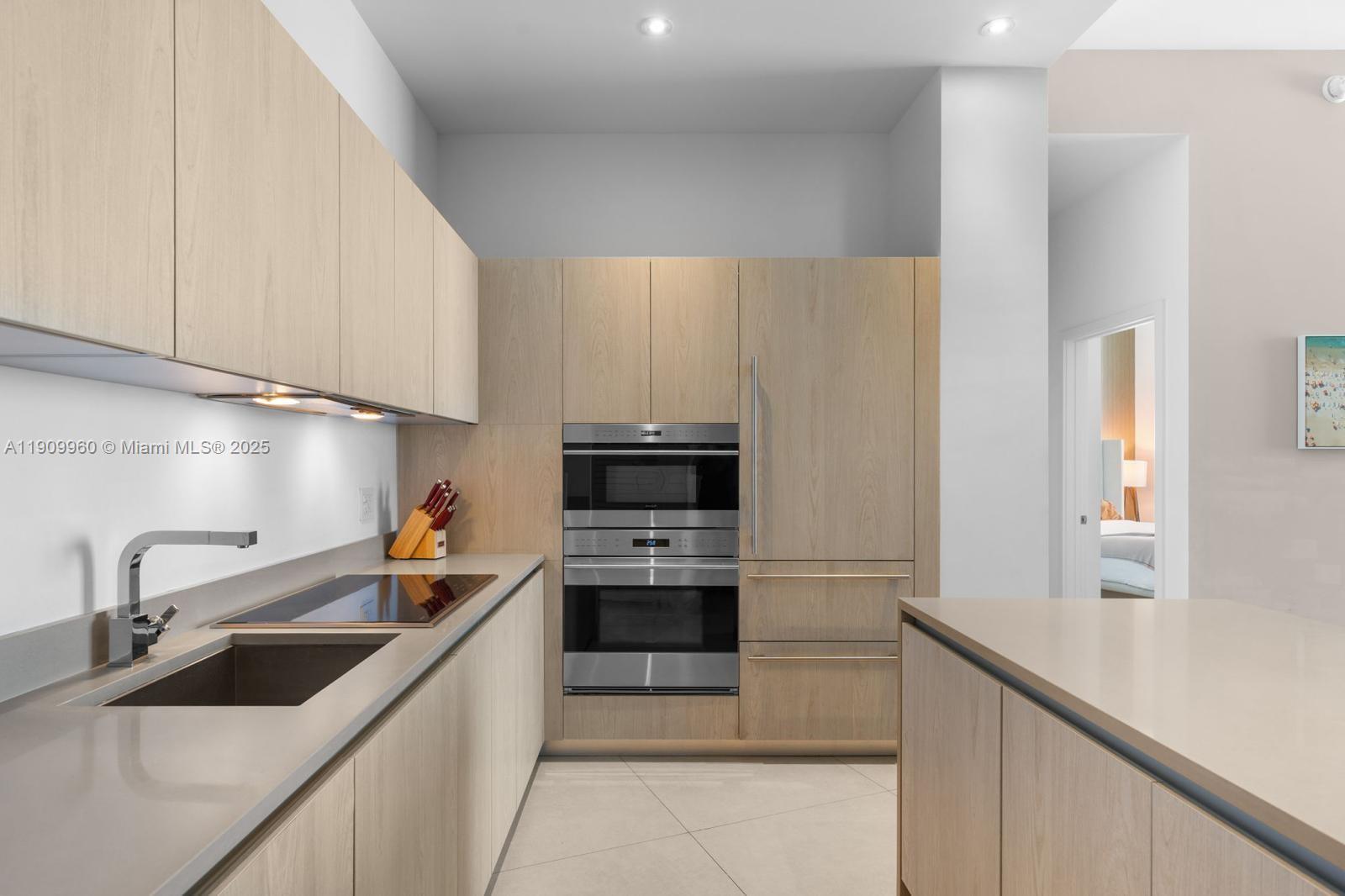A modern kitchen features light wood cabinetry, stainless steel appliances, and a stone countertop — 4111 S Ocean Dr # 502, Hollywood FL 33019, HOLLYWOOD, FL
