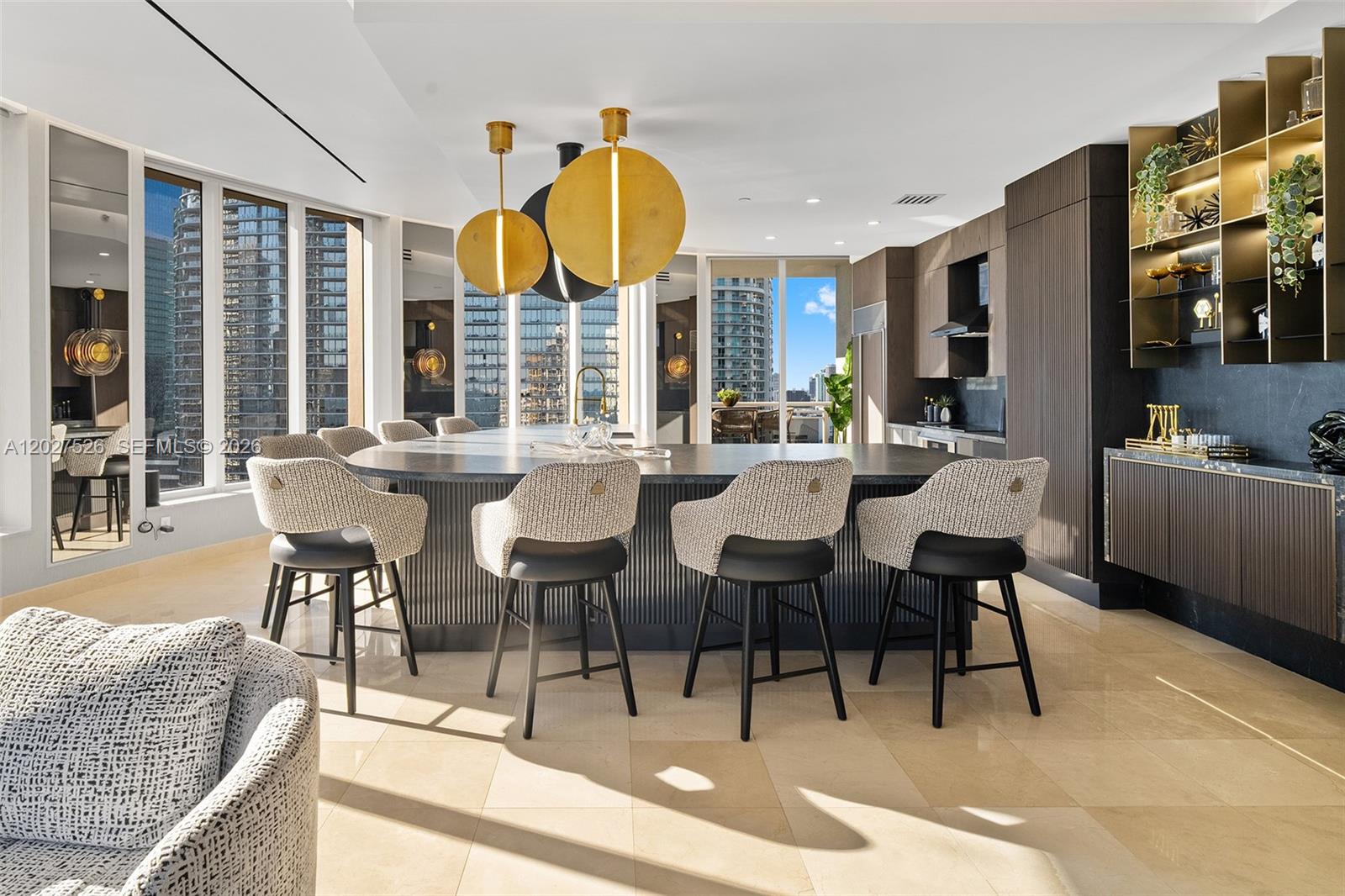 A modern kitchen features a large curved island with bar stools and gold pendant lights — 901 Brickell Key Blvd # 3304, Miami FL 33131, MIAMI, FL