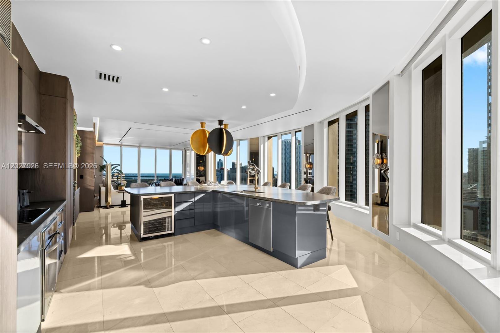 A modern kitchen features a large grey island, stainless steel appliances, and floor-to-ceiling windows — 901 Brickell Key Blvd # 3304, Miami FL 33131, MIAMI, FL