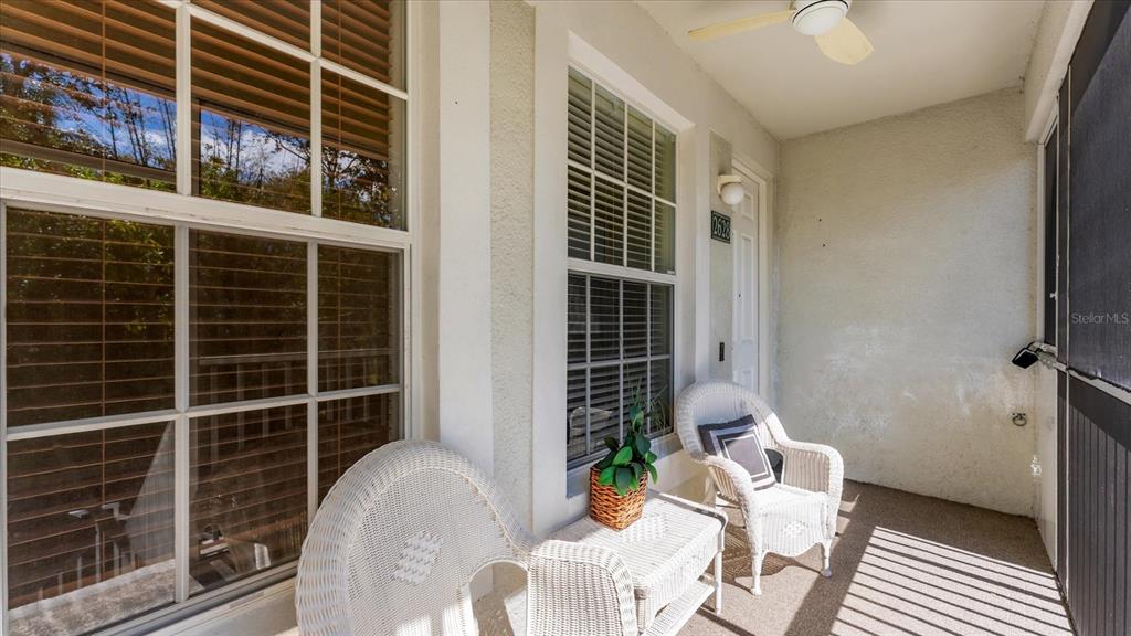 A covered patio features two white wicker chairs, a small table, and large windows — 2628 RIVER PRESERVE COURT UNIT 2628, BRADENTON, FL