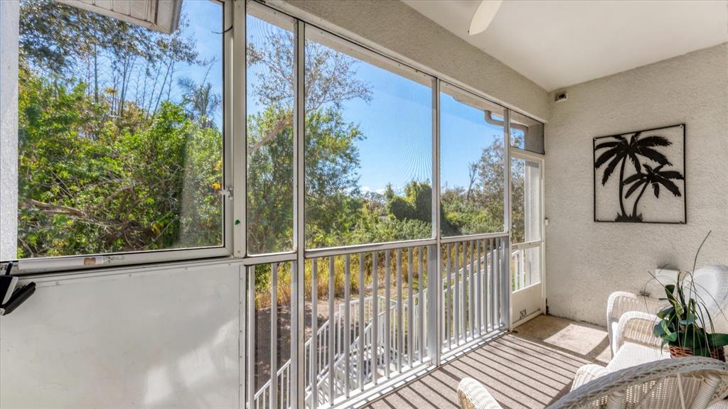 A screened-in porch features white railings, wicker furniture, and a view of surrounding trees — 2628 RIVER PRESERVE COURT UNIT 2628, BRADENTON, FL