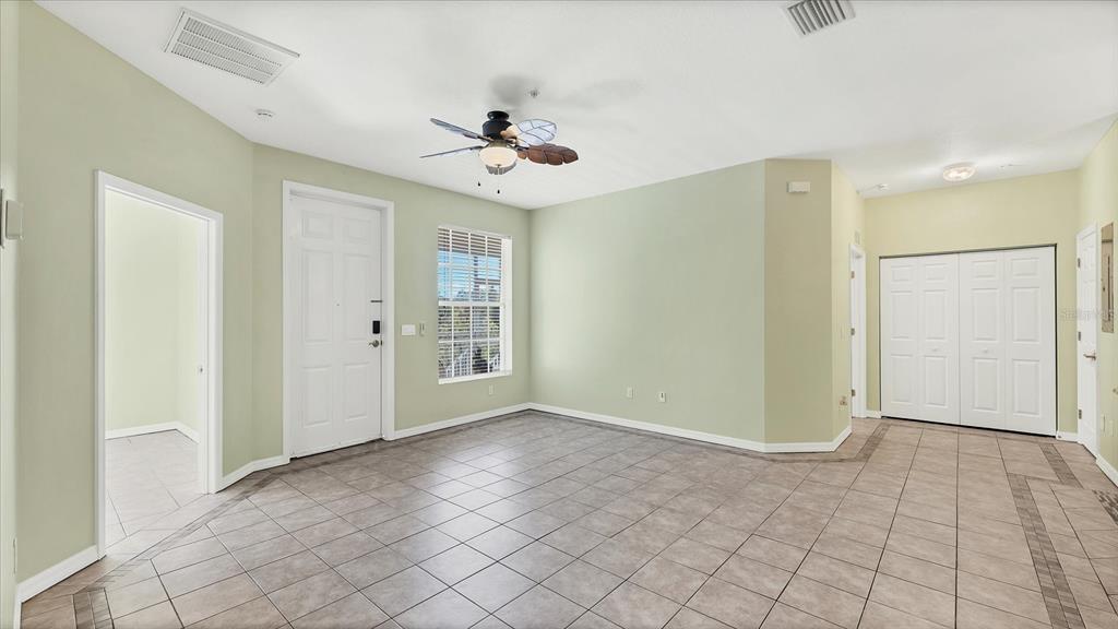 An empty room with light green walls, tile flooring, a ceiling fan, and white doors — 2628 RIVER PRESERVE COURT UNIT 2628, BRADENTON, FL