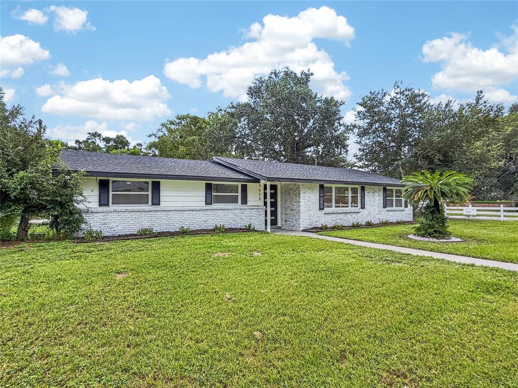 A single-story ranch-style house with a white brick exterior and a dark shingled roof — 3629 S CRYSTAL LAKE DRIVE, ORLANDO, FL