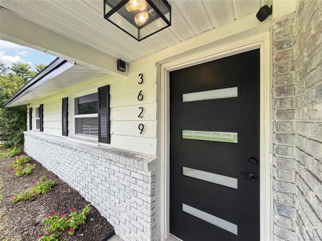 A black front door with horizontal glass panels sits next to white brick siding — 3629 S CRYSTAL LAKE DRIVE, ORLANDO, FL