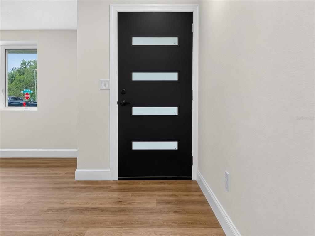 An interior view shows a black front door with four horizontal glass panels and flooring — 3629 S CRYSTAL LAKE DRIVE, ORLANDO, FL