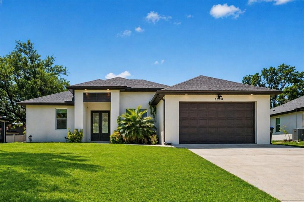 A single-story house with a white stucco exterior, dark roof, and a two-car garage — 3090 QUARTER STREET, NORTH PORT, FL