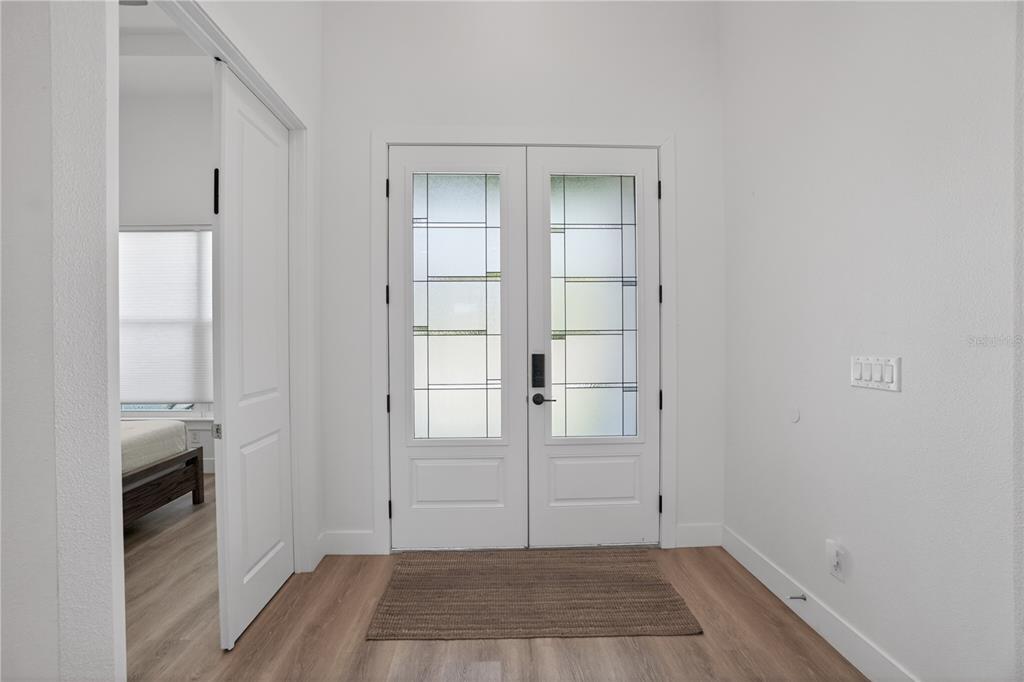 An entryway with light wood flooring, white walls, and double doors with frosted glass panels — 3090 QUARTER STREET, NORTH PORT, FL