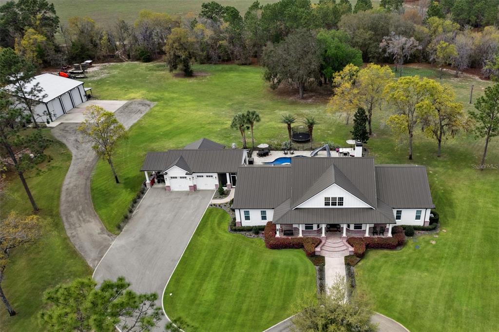 An aerial view shows a white house with a metal roof, pool, and detached garage — 2870 NW 87TH AVENUE, WILDWOOD, FL