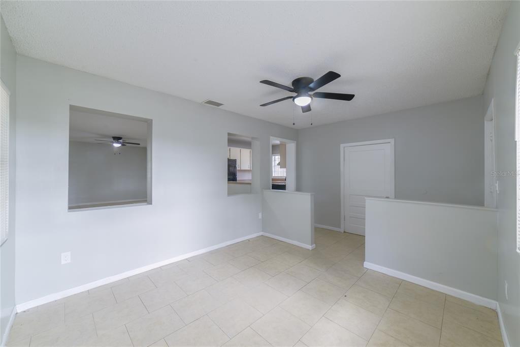An interior room with light gray walls, tile flooring, a ceiling fan, and wall cutouts — 14341 DELMAR STREET, DADE CITY, FL