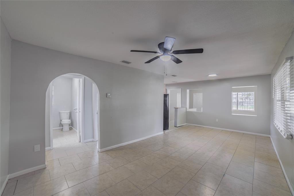An interior view of a room with light-colored tile flooring, gray walls, and an arched doorway — 14341 DELMAR STREET, DADE CITY, FL