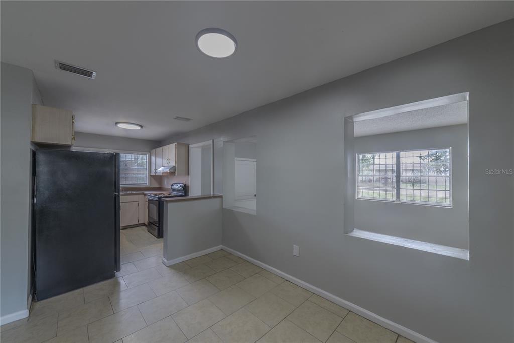 A kitchen with light tile floors, gray walls, and a large pass-through window — 14341 DELMAR STREET, DADE CITY, FL