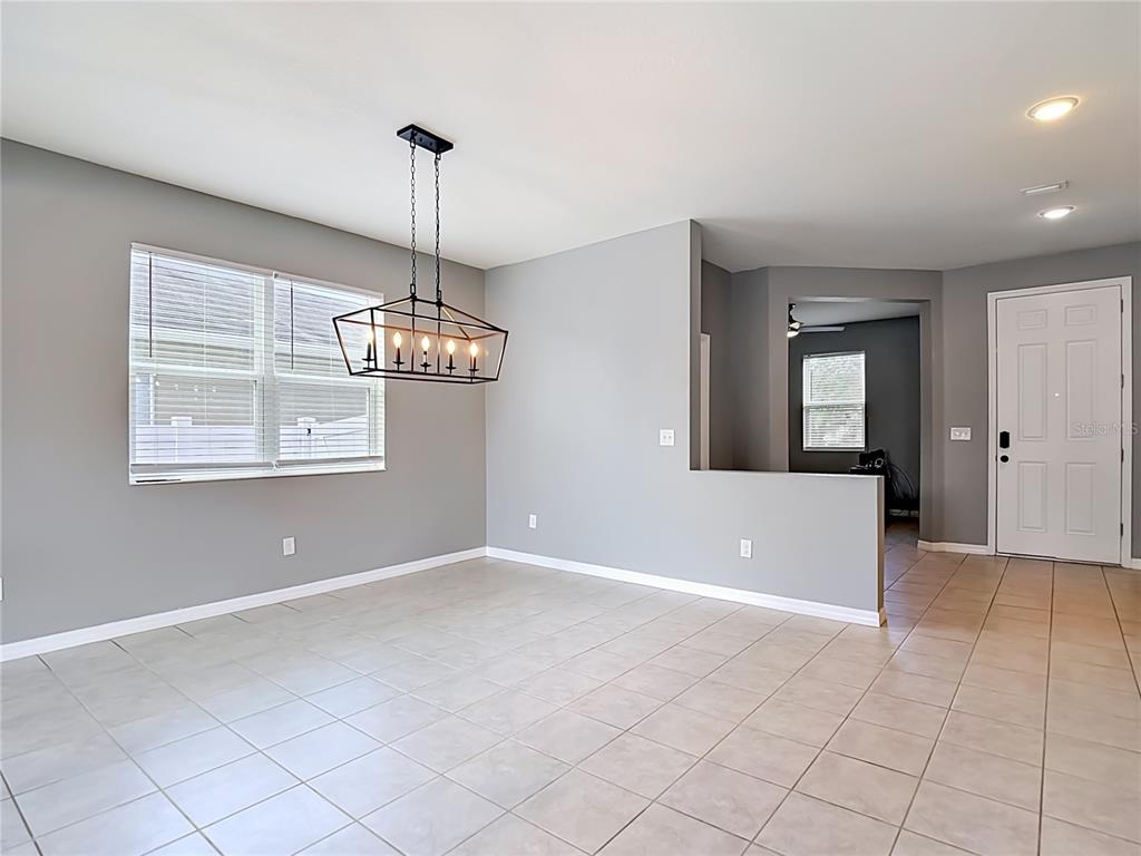 An empty dining area features gray walls, tile flooring, and a rectangular metal chandelier — 9127 FREEDOM HILL DRIVE, SEFFNER, FL
