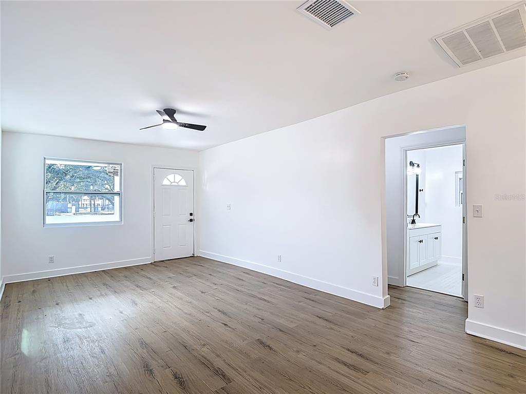 A room with wood-look flooring, a ceiling fan, a window, a door, and an attached bathroom — 402 E VIRGINIA AVENUE, TAMPA, FL