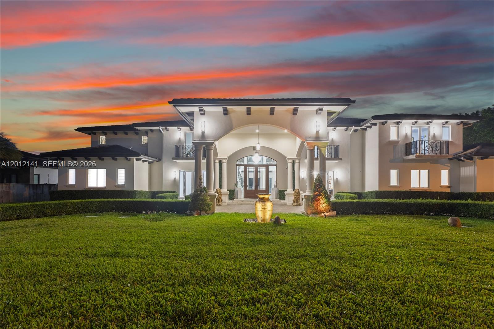 A large, two-story Mediterranean-style house with a central arched entryway and a manicured lawn — 12401 SW 45th St, Miami FL 33175, MIAMI, FL