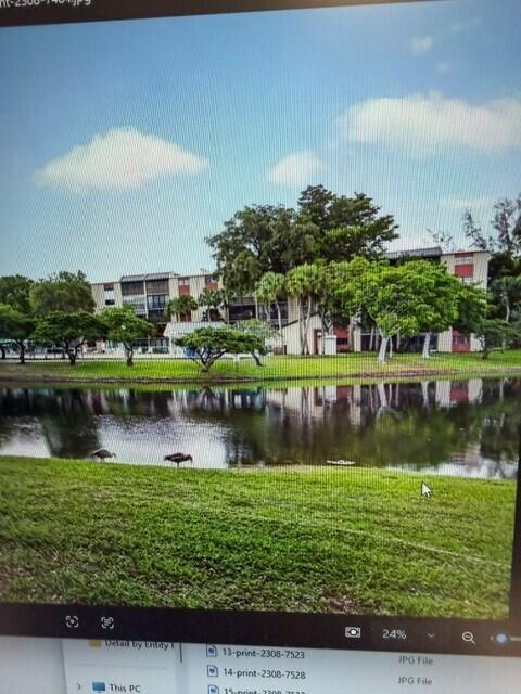 A multi-story apartment building sits behind a pond with two birds on the grassy bank — 2308 S Cypress Bend Drive # 123, Pompano Beach FL 33069, POMPANO BEACH, FL