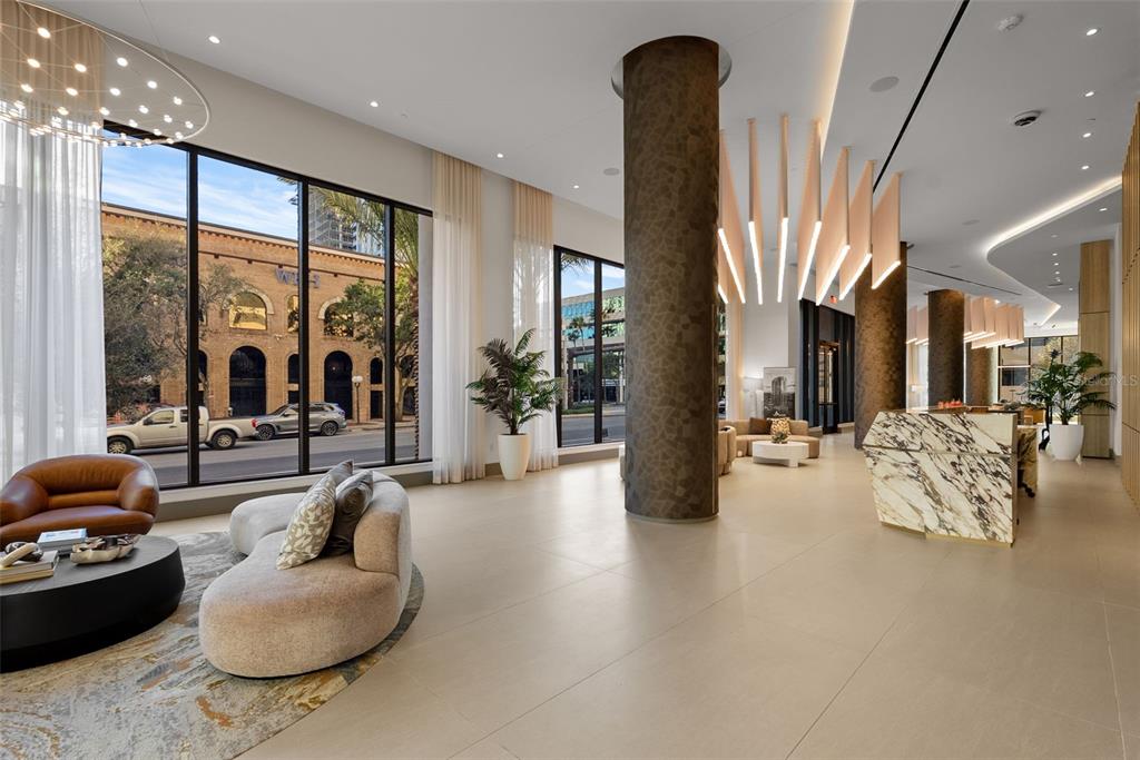 A modern lobby features a marble reception desk, large windows, and decorative pendant lighting — 275 1ST AVENUE S UNIT 3405, ST PETERSBURG, FL