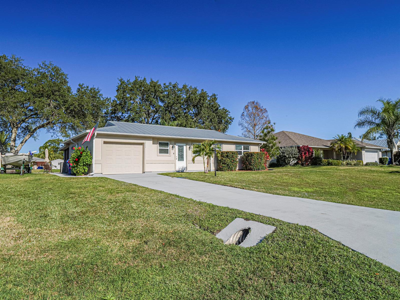 A single-story house with a metal roof, beige siding, and a concrete driveway — 255 Joy Haven Drive, Sebastian FL 32958, SEBASTIAN, FL