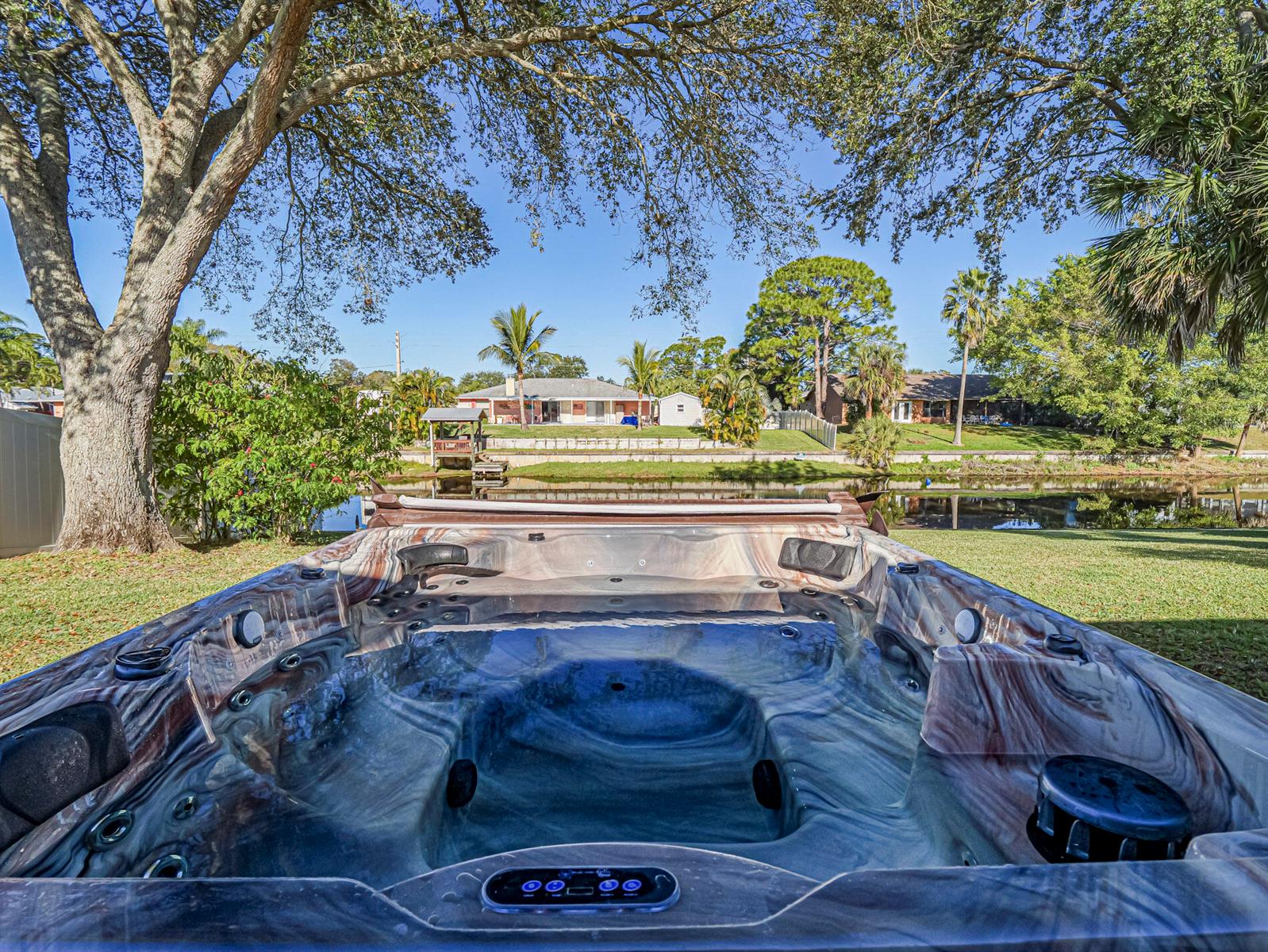 A hot tub sits on a grassy lawn overlooking a canal and neighboring houses — 255 Joy Haven Drive, Sebastian FL 32958, SEBASTIAN, FL
