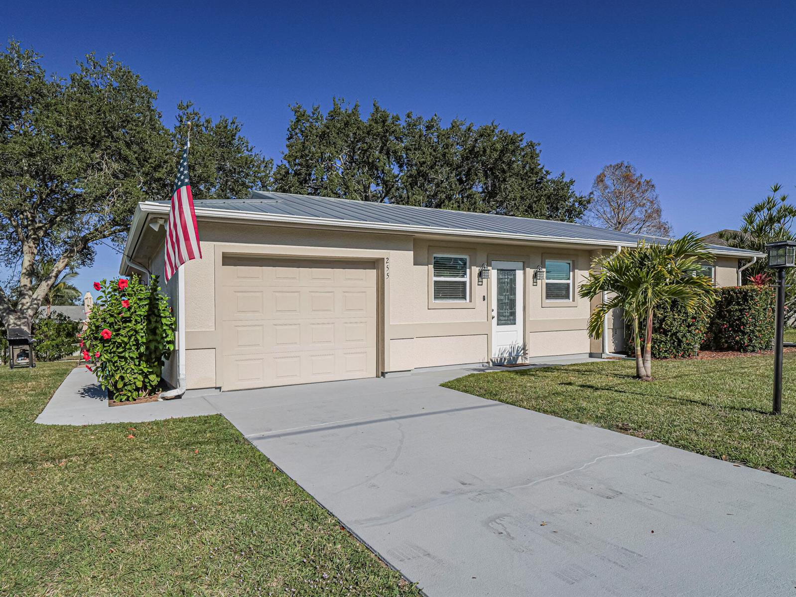 A single-story house with a beige stucco exterior, metal roof, and a concrete driveway — 255 Joy Haven Drive, Sebastian FL 32958, SEBASTIAN, FL