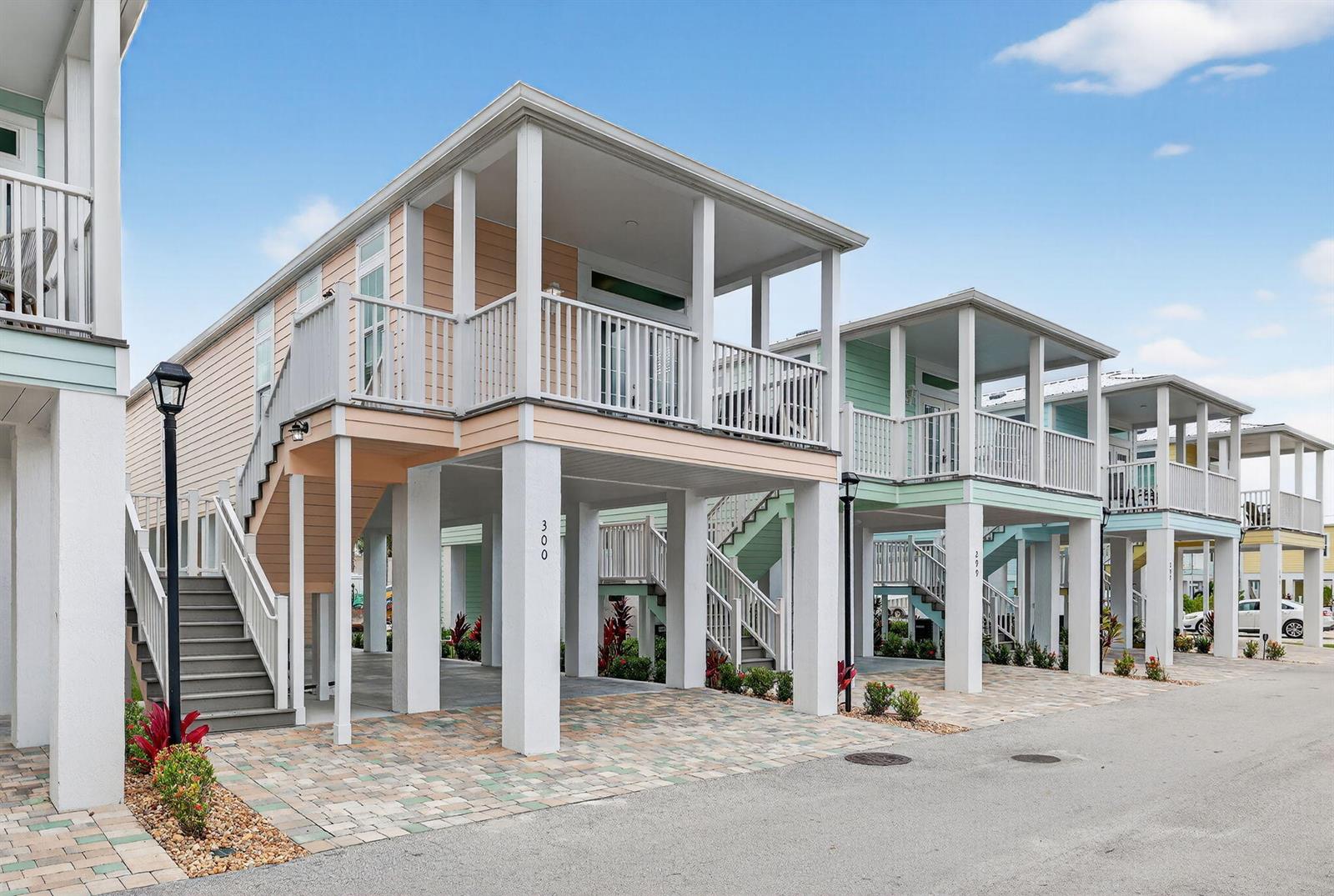 A row of elevated, pastel-colored stilt houses with front porches and paved driveways — 300 NE Coastal Drive, Jensen Beach FL 34957, JENSEN BEACH, FL