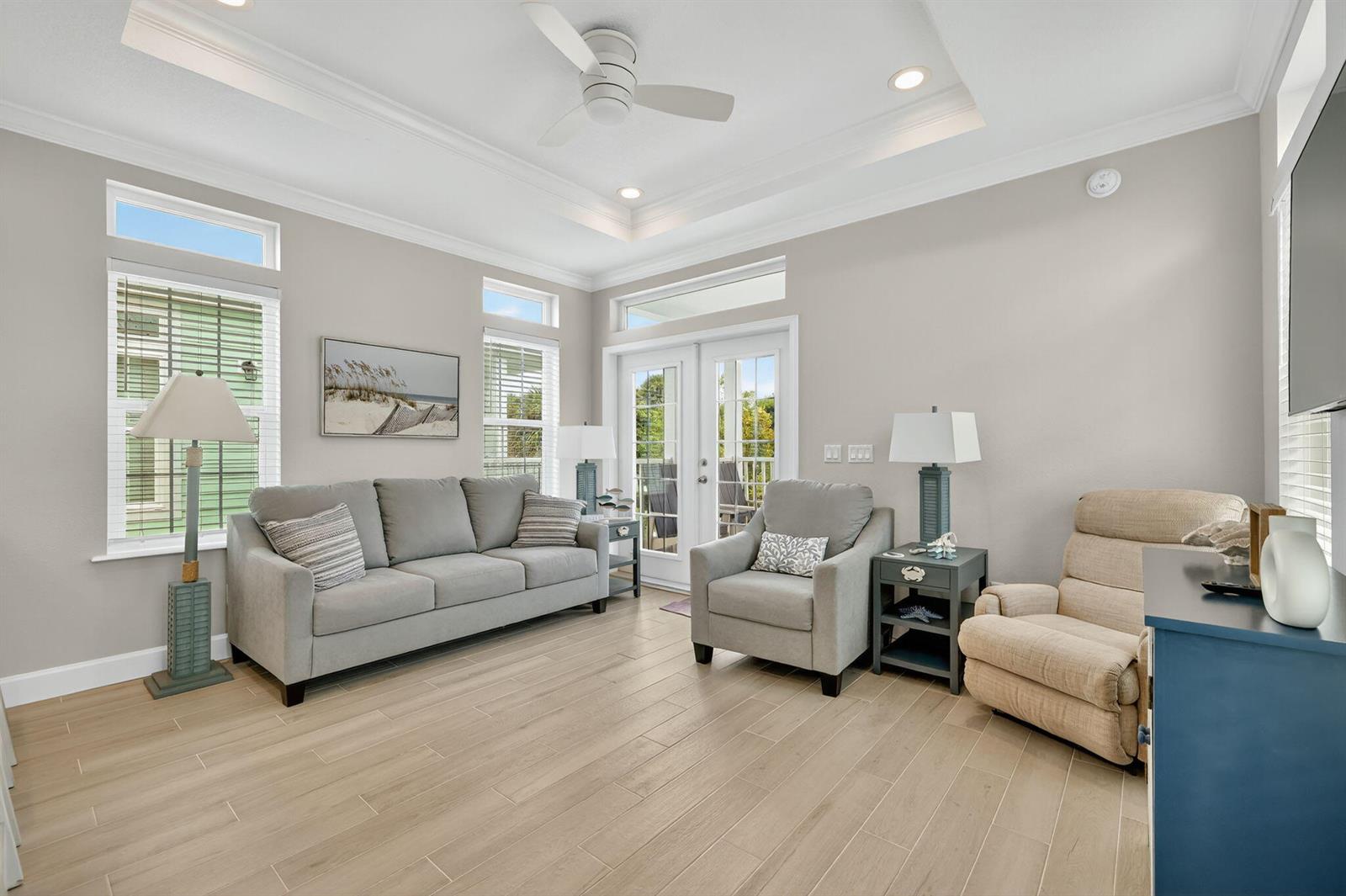 A living room features light gray walls, wood-look tile flooring, a tray ceiling, and furniture — 300 NE Coastal Drive, Jensen Beach FL 34957, JENSEN BEACH, FL