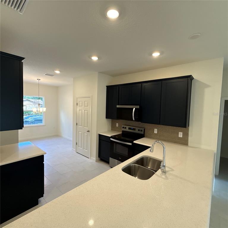 A kitchen features dark cabinets, white countertops, stainless steel appliances, and a breakfast nook area — 122 WELLSTONE DRIVE, PALM COAST, FL