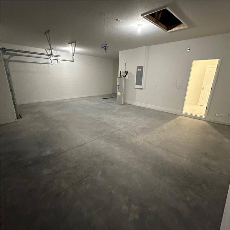 An unfinished garage with a concrete floor, water heater, and an open doorway — 122 WELLSTONE DRIVE, PALM COAST, FL