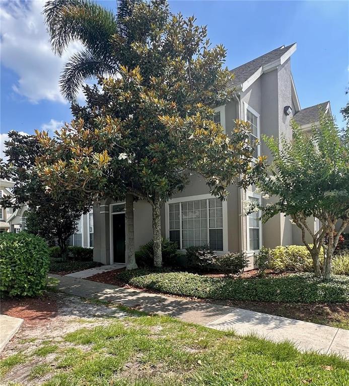 A two-story house with gray siding, a front entrance, and mature trees in the yard — 9021 LEE VISTA BOULEVARD UNIT 1711, ORLANDO, FL