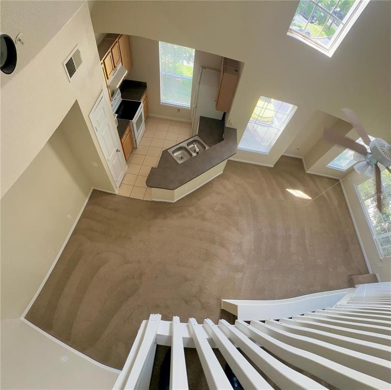 An elevated view of a living room with carpeted floors and an adjacent open kitchen — 9021 LEE VISTA BOULEVARD UNIT 1711, ORLANDO, FL